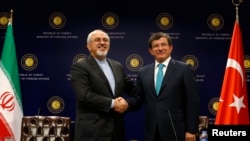 Iranian Foreign Minister Mohammad Javad Zarif (L) shakes hands with his Turkish counterpart Ahmet Davutoglu after a news conference in Ankara November 1, 2013.