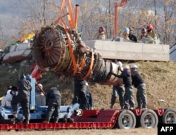 Sejumlah pekerja mengangkat mesin pesawat Boeing 737-800 yang digunakan oleh Jeju Air, yang mengalami kecelakaan fatal saat mendarat di Bandara Internasional Muan, di Muan, Jumat, 3 Januari 2024. (Foto: Yonhap/AFP)