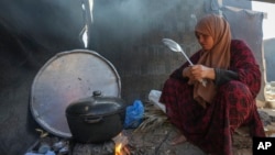 Yasmin Eid cooks at her family's tent in a refugee camp in Deir al-Balah, Gaza Strip, Nov. 19, 2024.