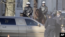 A funeral home limousine passes policemen near the New Hope Baptist Church in Newark, New Jersey, February 18, 2012.