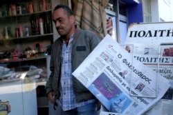 Seorang pria membaca berjalan melewati koran Siprus dengan halaman depan membawa foto montase tentang tindakan Turki atas Siprus dan eksplorasi perusahaan internasional untuk gas di Mediterania timur di ibukota Nicosia, Siprus, 13 Februari 2018. (Foto: AP)
