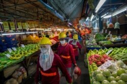 Migrant construction workers, wearing face masks to protect against coronavirus, walk through a market after concluding day's work in Bangkok, Thailand, April 9, 2020.
