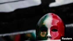 FILE - A member of the Casapound far-right organization wears a mask in the colors of the Italian flag before a demonstration organized by "People from pitchfork movement" to protest against economic insecurity and the government in Rome, Dec. 18, 2013.