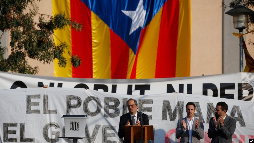 FILE - Catalan regional President Quim Torra, center, applauds in front of a large Catalonia independence flag during a rally in Sant Julia de Ramis, Spain, Oct. 1, 2018. Tensions appear to be growing between the two main Catalan secessionist parties.