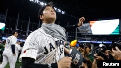 Japan designated hitter Shohei Ohtani (16) puts on a champions shirt after defeating the USA in the World Baseball Classic at LoanDepot Park, Miami, Florida, March 21, 2023. Rhona Wise-USA TODAY Sports