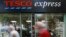 FILE - Tesco, Britain's largest retailer by revenue, plunged to an annual loss of 6.4 billion pounds ($9.5 billion) Wednesday. Pedestrians pass a Tesco shop in London, Sept. 22, 2014. 