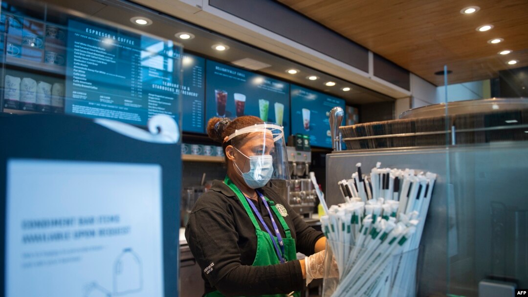 Seorang pegawai Starbucks mengenakan masker sambil menyiapkan pesanan pelanggan di Bandara Ronald Reagan Washington di Arlington, Virginia, 12 Mei 2020.