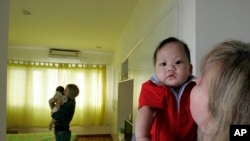 FILE - Monica DiGioacchino, right, of Alameda, Calif., holds her new adopted 7-month-old Vietnamese baby Patrick, as her roommate Tracy Sumner, background, of Richmond, Va., also holds her new adopted 5-month-old Vietnamese baby, Hanoi,Vietnam.