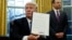 U.S. President Donald Trump holds up the executive order on the reinstatement of the Mexico City Policy after signing in the Oval Office of the White House in Washington, Jan. 23, 2017. 
