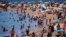 Bañistas se refrescan en el agua mientras otros toman el sol en una playa de Barcelona, España, el 24 de julio de 2024. 