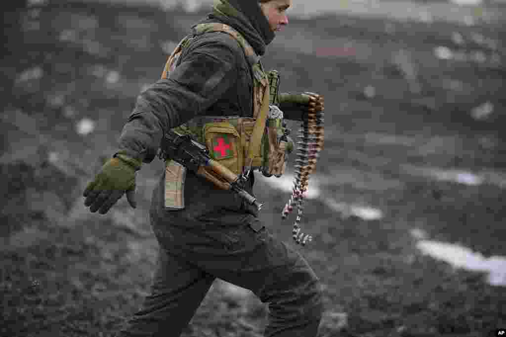 A Ukrainian serviceman runs to deliver ammunition to an armored fighting vehicle during a live fire exercise in a Joint Forces Operation controlled area in the Donetsk region, eastern Ukraine.