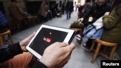 FILE - A man tries to get connected to the YouTube web site with his tablet at a cafe in Istanbul, Turkey, March 27, 2014. Turkey's media regulator wants journalists who operate their own YouTube channels to have broadcast licenses.