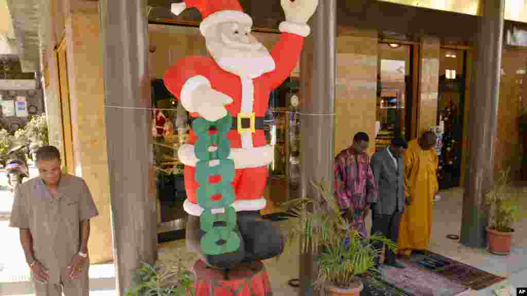 Des musulmans assistent à la prière du vendredi après-midi à côté d'un Père Noël gonflable près d’une boulangerie dans le centre de Dakar, au Sénégal, 16 décembre 2005.