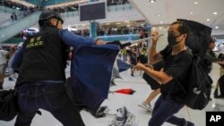 Polisi Hong Kong bentrok dengan seorang demonstran di dalam sebuah mall di distrik Sha Tin, hari Minggu (14/7). 