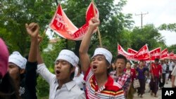 Buruh pabrik Myanmar memegang kain bertuliskan "Upah setidaknya 4.000 per hari," sementara melakukan reli di kota kecil Hlaingtharyar, di pinggiran Yangon, 12 Juli 2015.