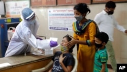 A girl reacts as a health worker collects her swab sample to test for COVID-19 in Mumbai, India, April 20, 2021. 