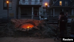 Shane Decarolis stands with his scooter next to a fire outside his home on Beach 91st street in the Rockaways section of the Queens borough of New York, November 3, 2012. 