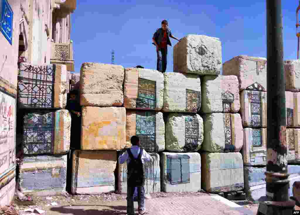 Children climb the stone barricade. The fake street sign, upper left, reads "Street without Walls." (VOA Photo - E. Arrott)