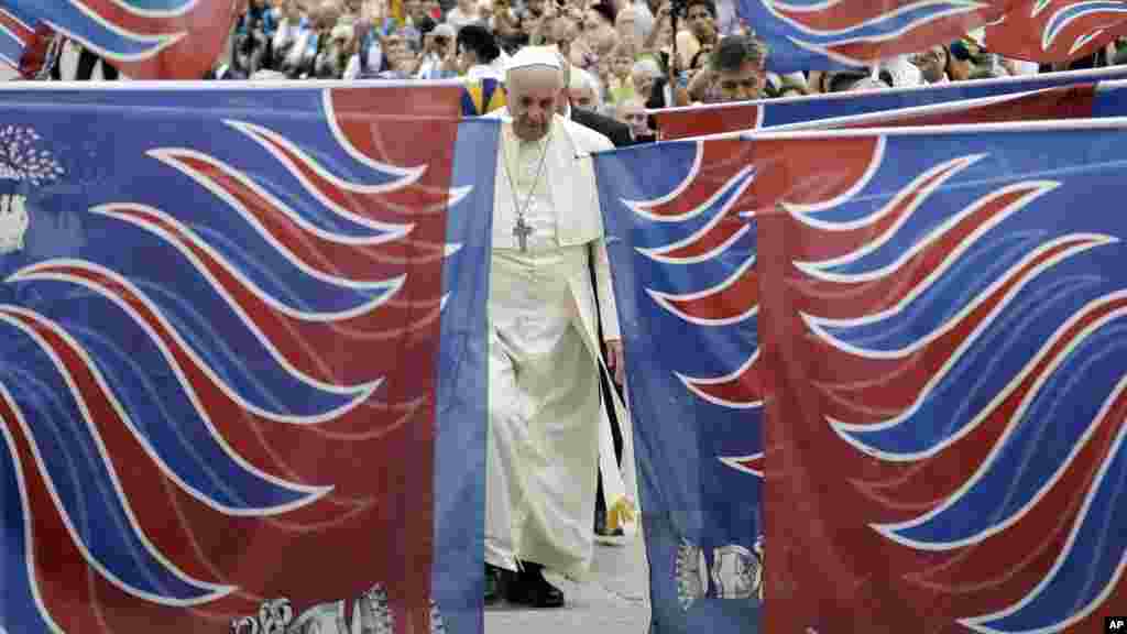 Le pape François est encadré par des drapeaux traditionnels d&#39;une délégation de fidèles de Carovigno, du Sud de l&#39;Italie, à son arrivée à la place Saint-Pierre pour assister à l&#39;audience générale hebdomadaire au Vatican, le 15 octobre 2014 (AP Photo / Gregorio Borgia) 