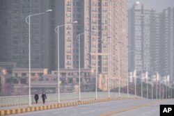 People wearing face masks walk down a deserted street in Wuhan in central China's Hubei Province, Jan. 28, 2020.