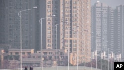 People wearing face masks walk down a deserted street in Wuhan in central China's Hubei Province, Jan. 28, 2020.