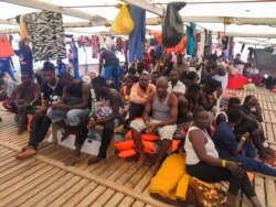 FILE - Migrants are seen aboard the Open Arms Spanish humanitarian boat as it cruises in the Mediterranean Sea, Aug. 9, 2019.