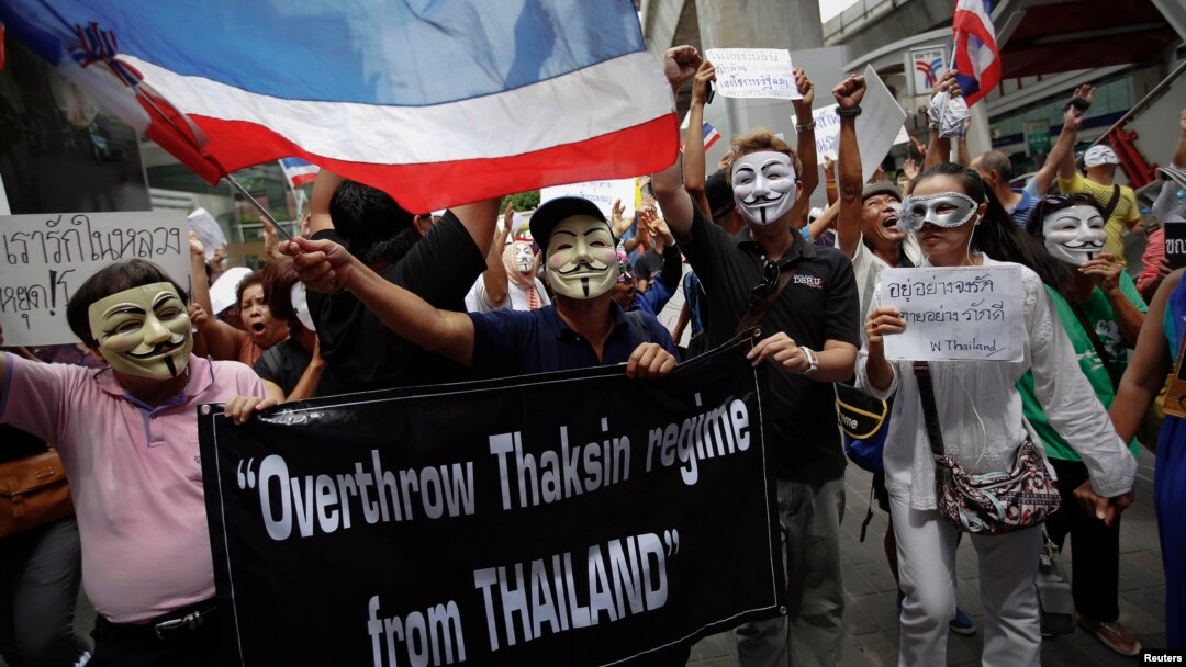 Protesters wearing masks shout slogans as they march though Bangkok's shopping district, June 2, 2013. 