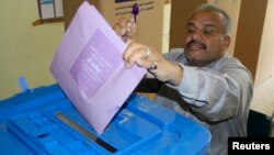 A man holds up his ink-stained finger as he casts his vote at a polling station in Baghdad, April 20, 2013. 