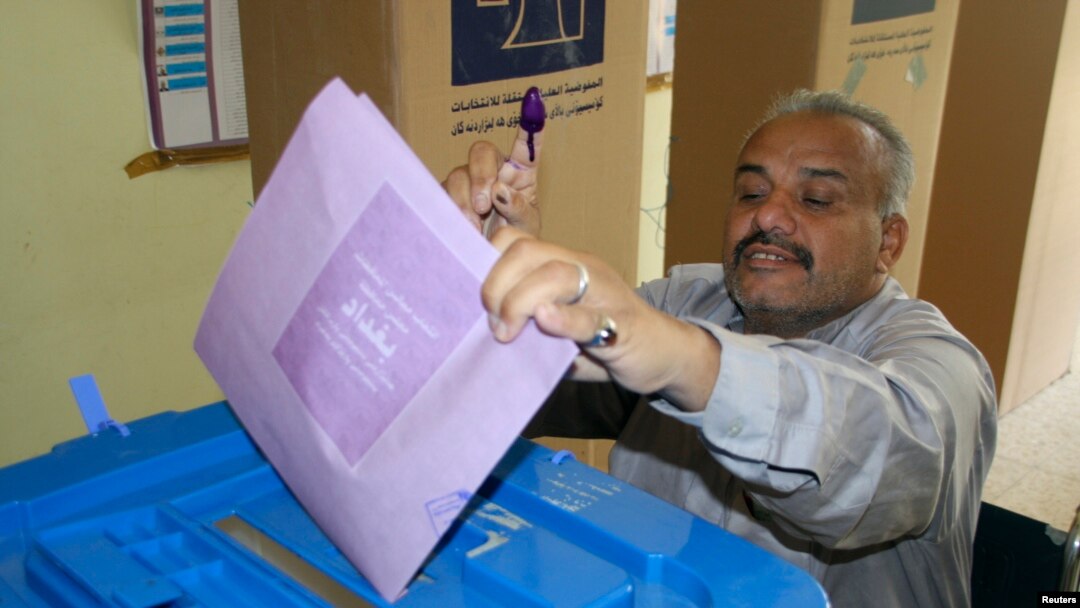 Seorang peserta pemilu memamerkan jarinya yang telah dicelup tinta sambil memasukkan surat suaranya ke dalam kotak di salah satu TPS di Baghdad (20/4).