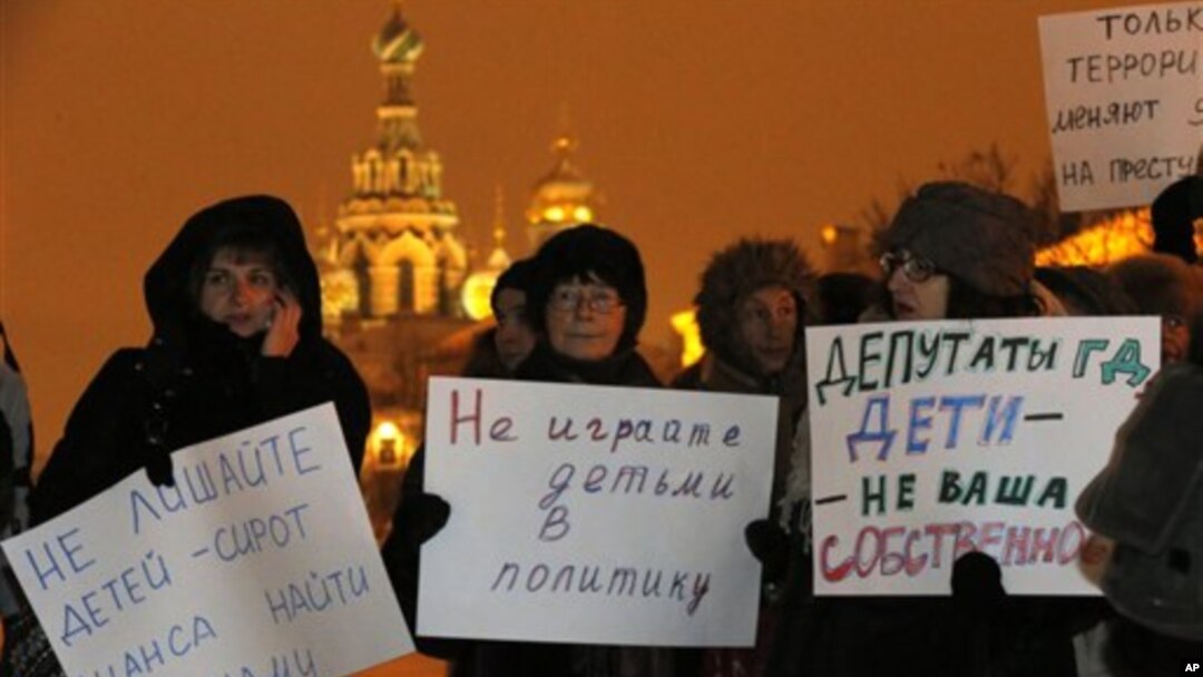 Para aktivis memegang poster bertuliskan "Jangan libatkan anak-anak dalam politik" dan "Pembuat hukum, anak-anak bukan milikmu" dalam protes di St. Petersburg (26/12) atas RUU yang melarang warga AS mengadopsi anak Rusia. (AP/Dmitry Lovetsky)