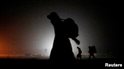 FILE - A group of migrants who said they were from Djibouti and Somalia walk along railway tracks after crossing the Canada-U.S. border in Emerson, Manitoba, Canada, March 27, 2017.