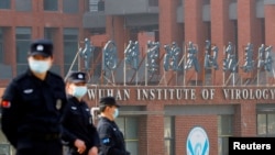 Petugas keamanan tampak berjaga di depan gedung Institut Virologi Wuhan di Wuhan, China, pada 3 Februari 2021, di saat sejumlah anggota WHO mengunjungi institut tersebut untuk menginvestigasi asal-usul COVID-19. (Foto: Reuters/Thomas Peter)