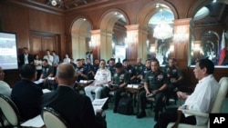 In this handout photo provided by the Malacanang Presidential Photographers Division, Philippine President Rodrigo Duterte, right, talks with security officials at the Malacanang presidential palace in Manila, Jan. 5, 2020. 