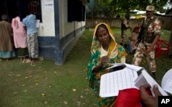 FILE - A woman checks her papers as villagers check their names in the final list of National Register of Citizens in Morigaon district, Assam, India, Aug. 31, 2019.
