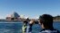 Seorang turis China berpose di depan Sydney Opera di Sydney (Foto: dok.)