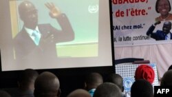 Members of the 'Young Patriots', a fanatical group supporting former Ivory Coast president Laurent Gbagbo, follow on a large screen court proceedings of Charles Ble Goude during his hearing at the International Penal Court (ICC), Oct. 2, 2014, in Abidjan.