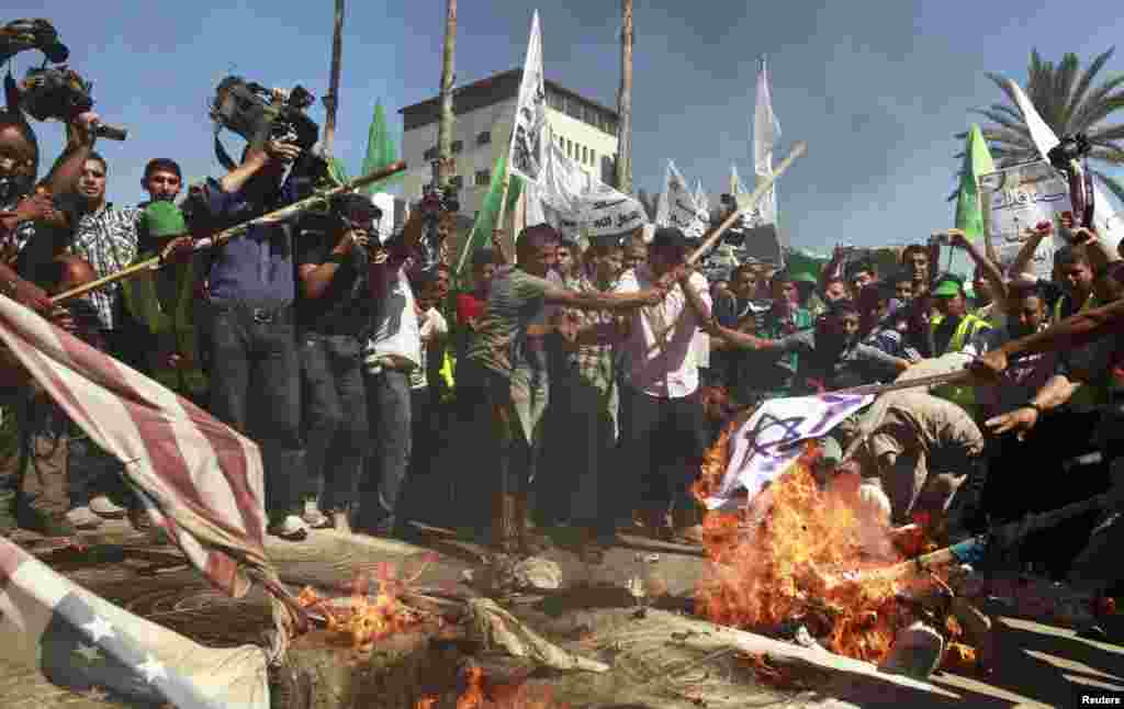 Warga Palestina membakar bendera AS dan Israel selama demonstrasi menentang film produksi AS yang menurut mereka menghina Nabi Muhammad, di kota Gaza (14/9). (Reuters)