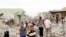 Residents stand amid rubble at blast scene in Tuz Khormato town in northern Iraq, May 21, 2013.