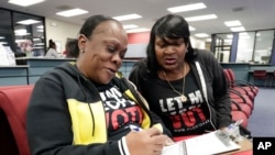 FILE - Former felon Yolanda Wilcox, left, fills out a voter registration form as her friend Gale Buswell looks on at the Supervisor of Elections office in Orlando, Fla., Jan. 8, 2019. 