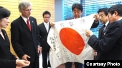 Japanese Prime Minister Shinzo Abe (C) examines the "good luck flag" that Dallas Britt took in battle and then returned 70 years later. Keiko and Rex Ziak stand at left. (Courtesy - Obon 2015)