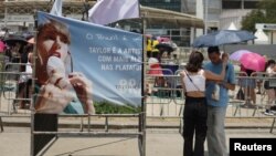 Una pareja se protege del sol con una sombrilla, a la espera del concierto de Taylor Swift en Rio de Janeiro, Brasil, este sábado 18 de noviembre de 2023.