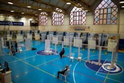 Israelis wait to receive coronavirus vaccine at a COVID-19 vaccination center, set up on a basketball court in Hod Hasharon, near Tel Aviv, Israel, Jan. 6, 2021.