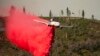 Pesawat pemadam kebakaran menyemprotkan retardant untuk menghentikan kebakaran lahan meluas di wilayah Mariposa, California, pada 24 Juli 2022. (Foto: AP/Noah Berger)
