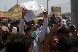 FILE - Hundreds of people gather, some holding documents, on Aug. 26, 2021, near an evacuation control checkpoint on the perimeter of the Hamid Karzai International Airport, in Kabul, Afghanistan.