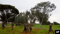 FILE - Israeli soldiers walk through a carpet of red anemone wildflowers in bloom in Re'im, southern Israel, February 12, 2024.