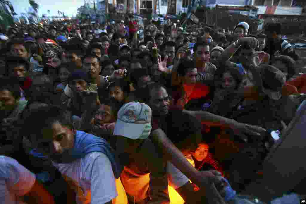 The brakelight of a delivery truck lights up a boy's face as survivors struggle to be the first in line during the distribution of relief goods in typhoon-hit Tacloban, Philippines, Nov. 18, 2013. 