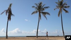 Seorang pengunjung pantai berjalan menyusuri Pantai Waikiki, Kamis, 15 Oktober 2020, di Honolulu. (Foto: AP)