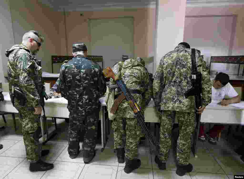 Para pria anggota milisia pro-Rusia bersenjata mendaftar sebelum memberikan suara di TPS dalam referendum di kota Slaviansk di Ukraina Timur (11/5).