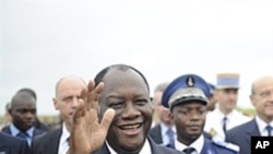 Ivory Coast President Alassane Ouattara waves next to French president Nicolas Sarkozy (not seen) on May 21, 2011 at the airport in Yamoussoukro
