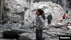 Dečak posmatra ruševine u Alepu nakon najnovijih napada na položaje pobunjenika